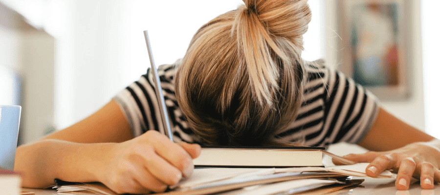 A student face down on a book on their desk